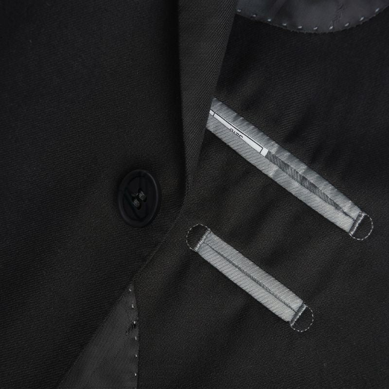 Close-up of a black tailored jacket or vest with a single visible black button and two diagonal silver-toned metal grommets or loops on the front.