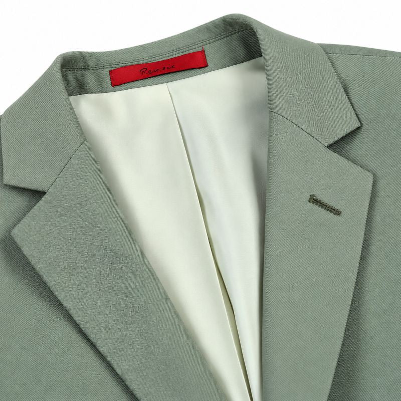 A close-up of a light sage green suit jacket with a white satin inner lining and a red interior neck label.