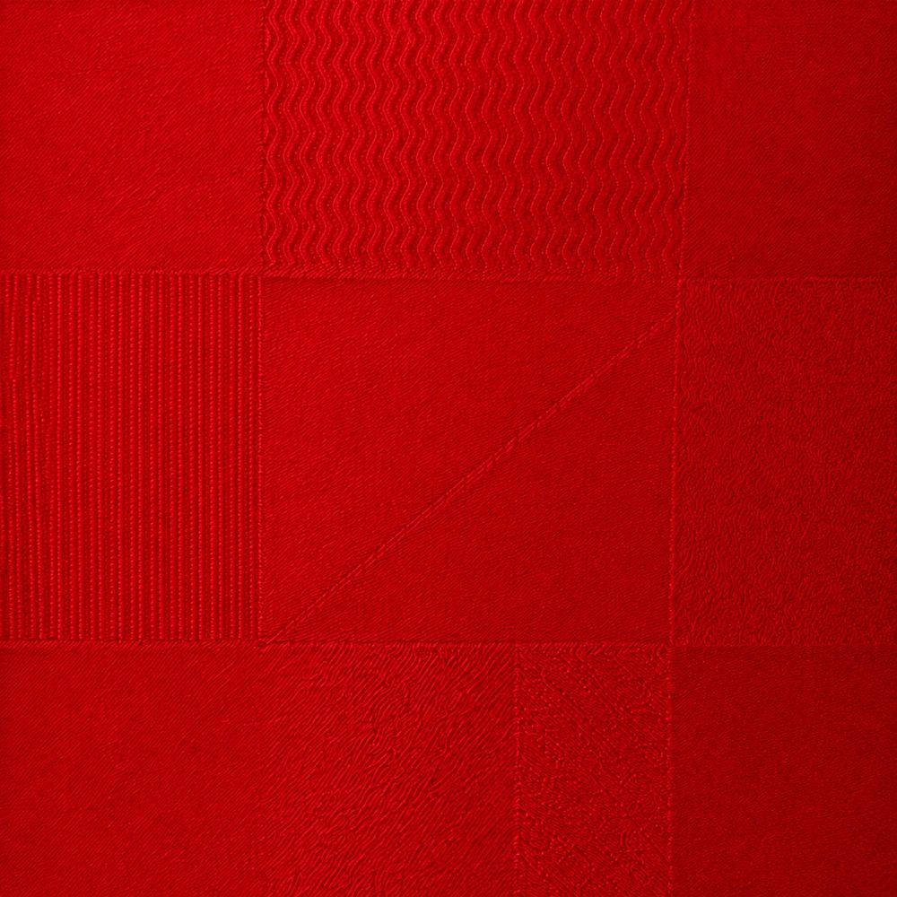 A close-up of a red textured fabric or material swatch with a patchwork-style grid pattern showing different weave and stitch textures.