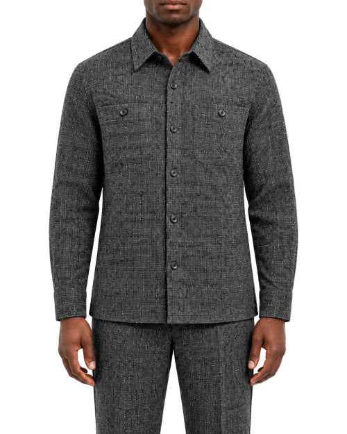 A man wearing a dark gray textured long-sleeve button-up shirt and matching gray trousers, shown from the chin down against a plain white studio background.