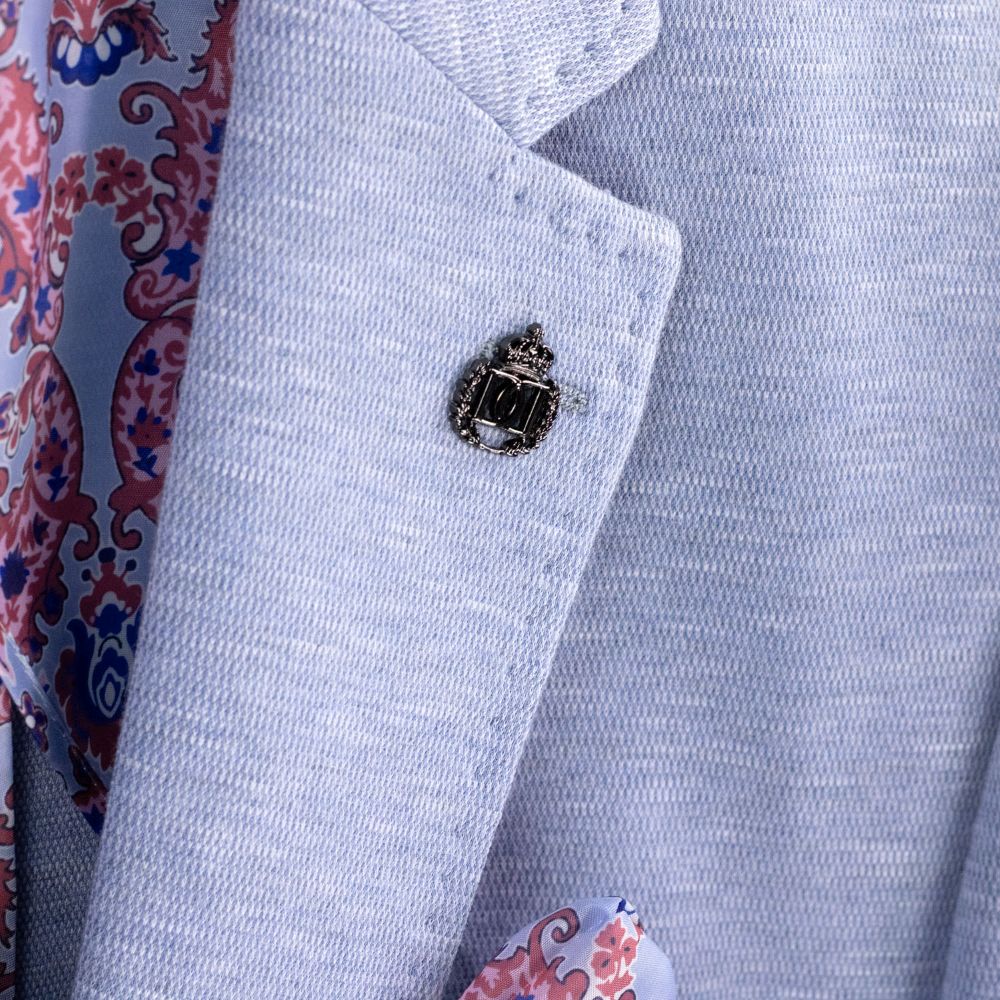 Close-up of a light blue textured fabric with a decorative emblem on a patterned background