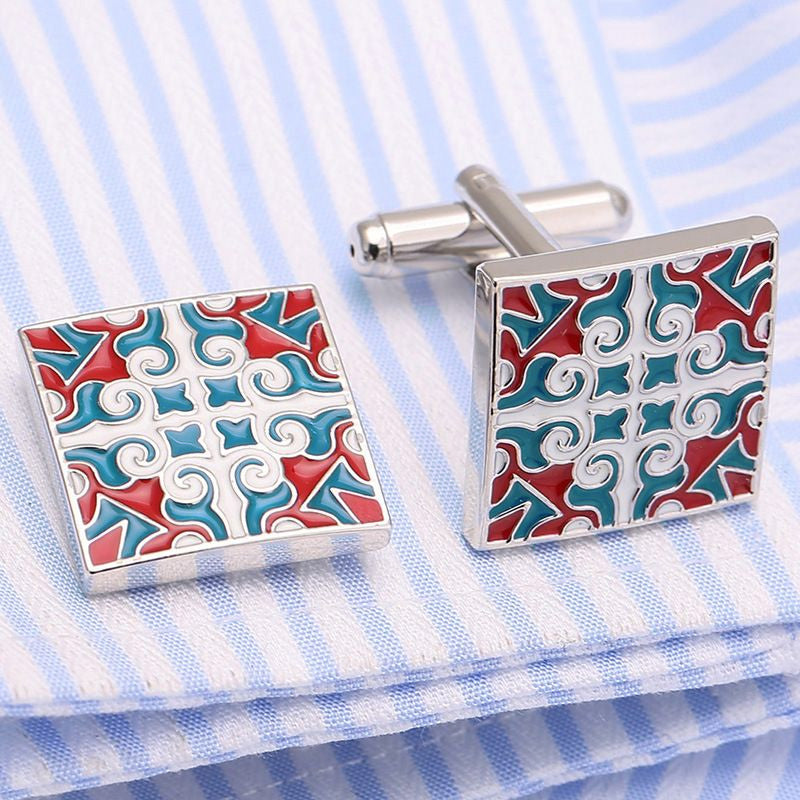 Pair of square cufflinks with a colorful pattern on a striped fabric background