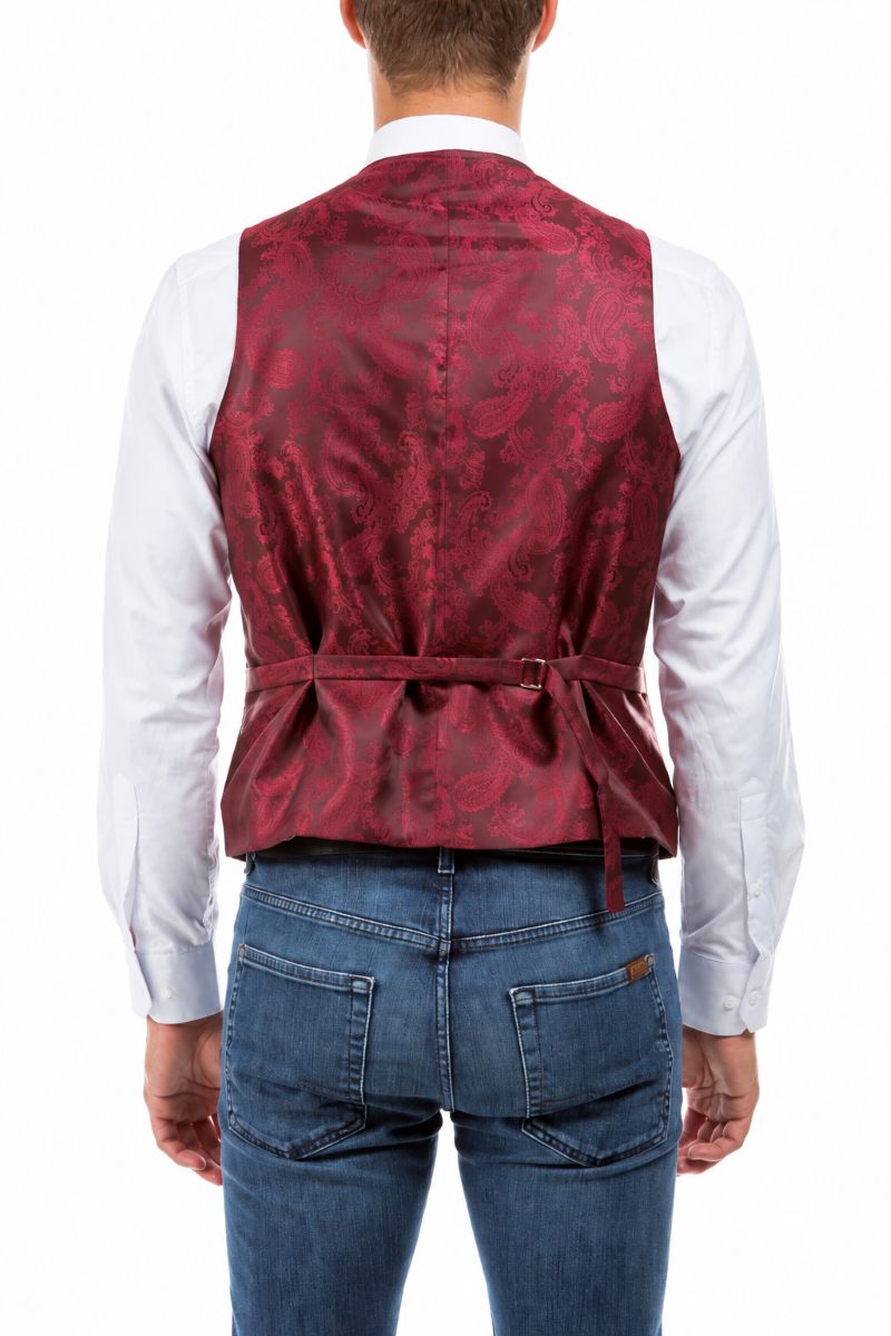 A man viewed from the back wearing a red paisley patterned waistcoat vest over a white long-sleeve shirt and blue jeans, against a plain white background.
