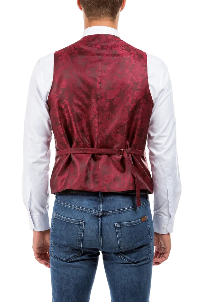 A man viewed from the back wearing a red paisley patterned waistcoat vest over a white long-sleeve shirt and blue jeans, against a plain white background.