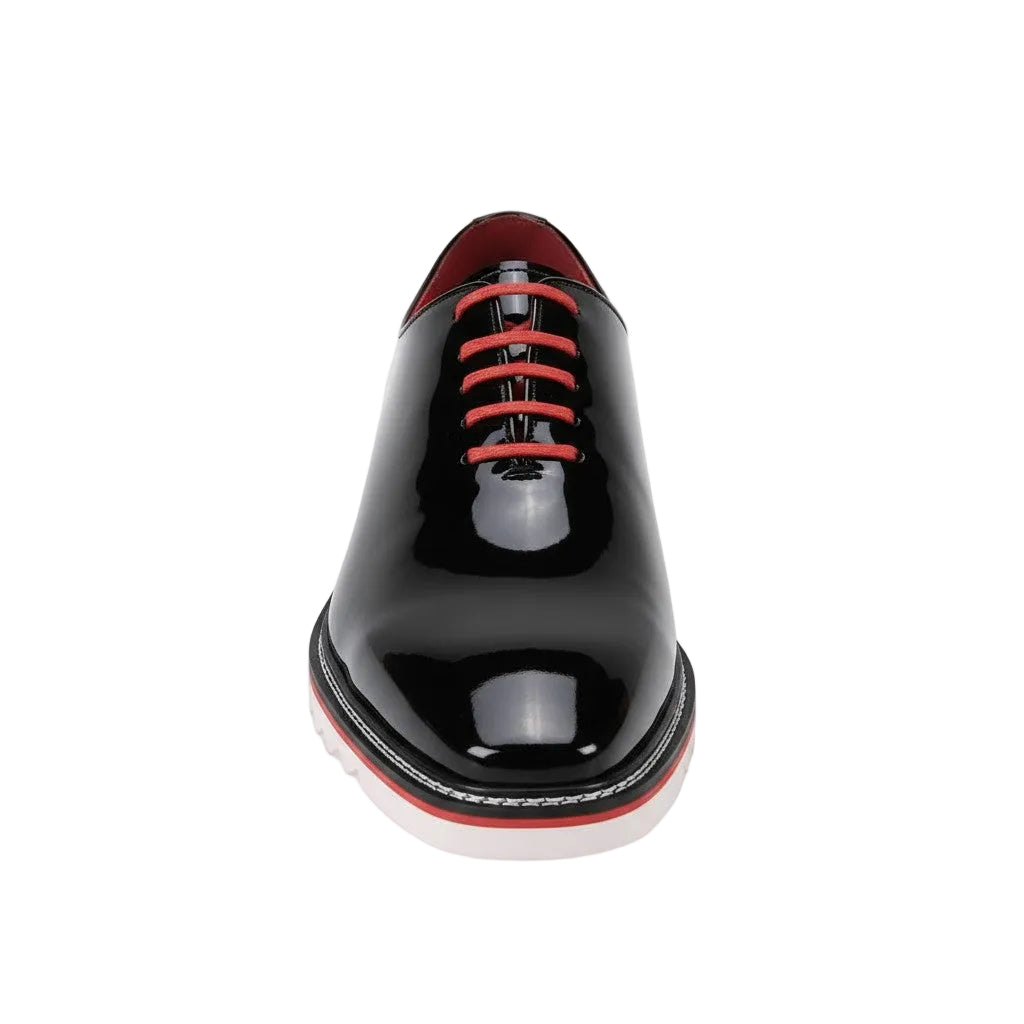 Black patent leather shoe with red laces on a white background