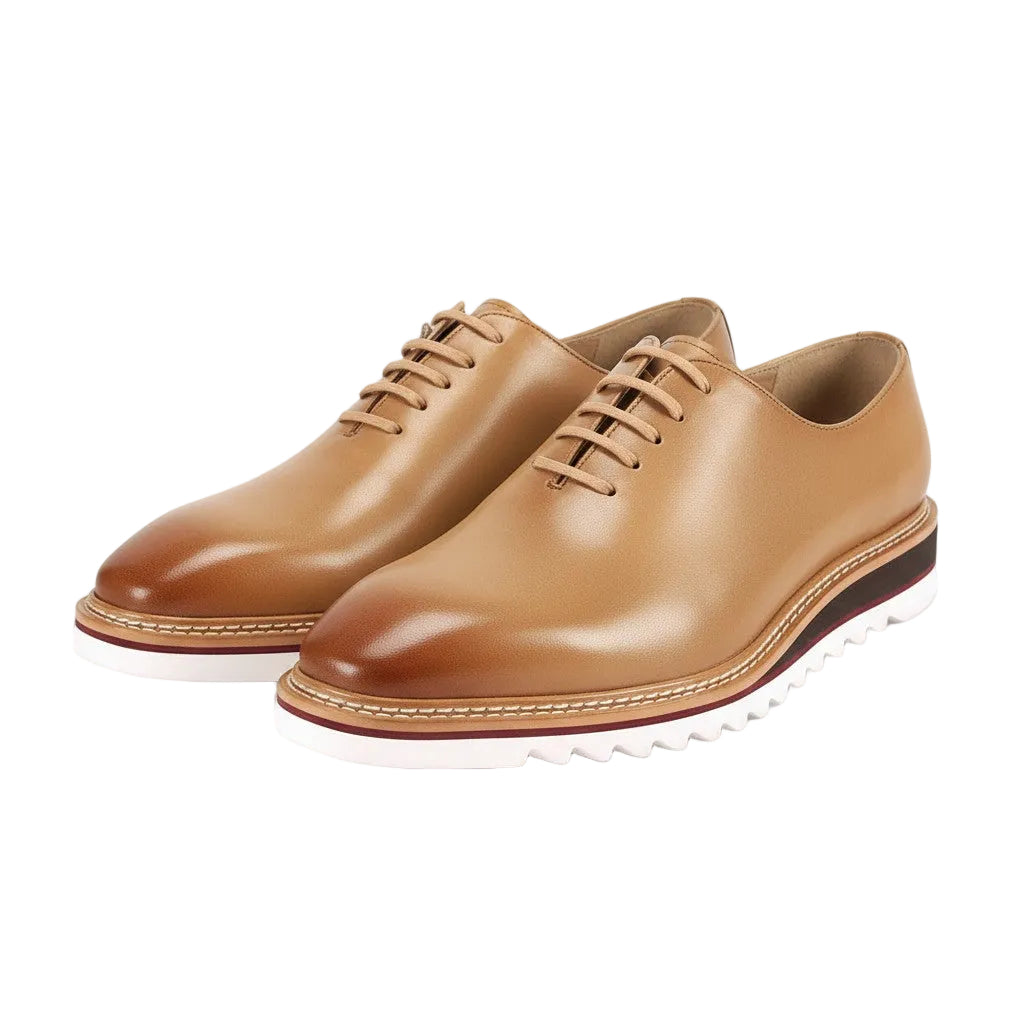 Pair of latte leather shoes with white soles on a white background