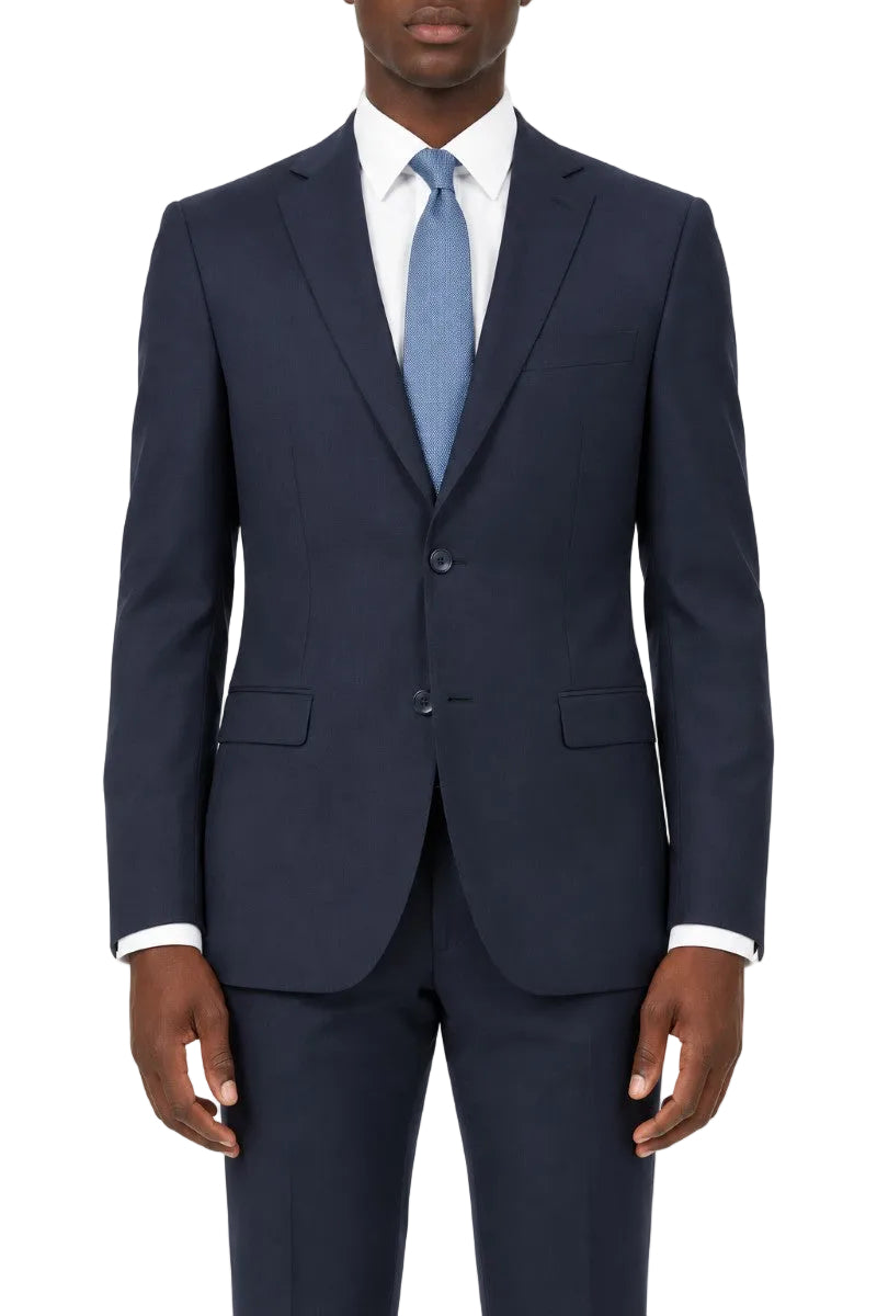 A man wearing a navy blue two-piece suit with a white dress shirt and a light blue tie, shown from the waist up against a plain white background.