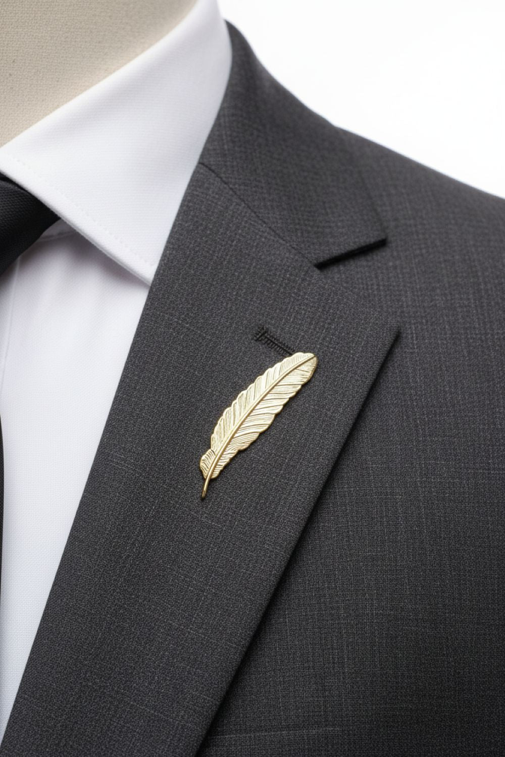 Gold feather lapel pin on a gray suit jacket