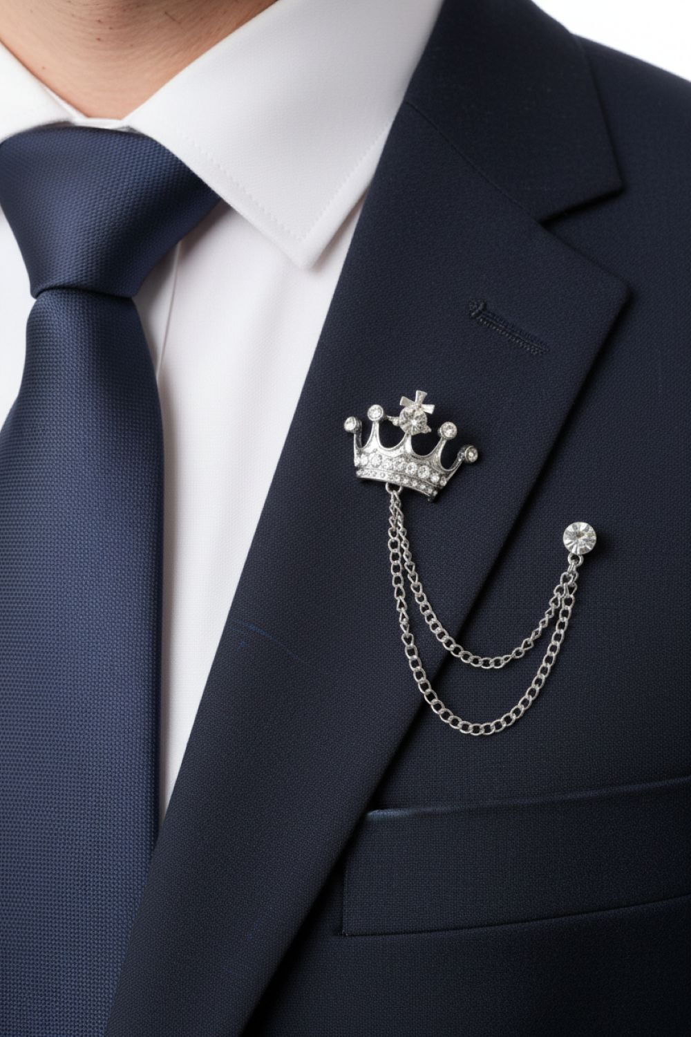 Crown-shaped lapel pin on a suit jacket with a blue tie and white shirt.