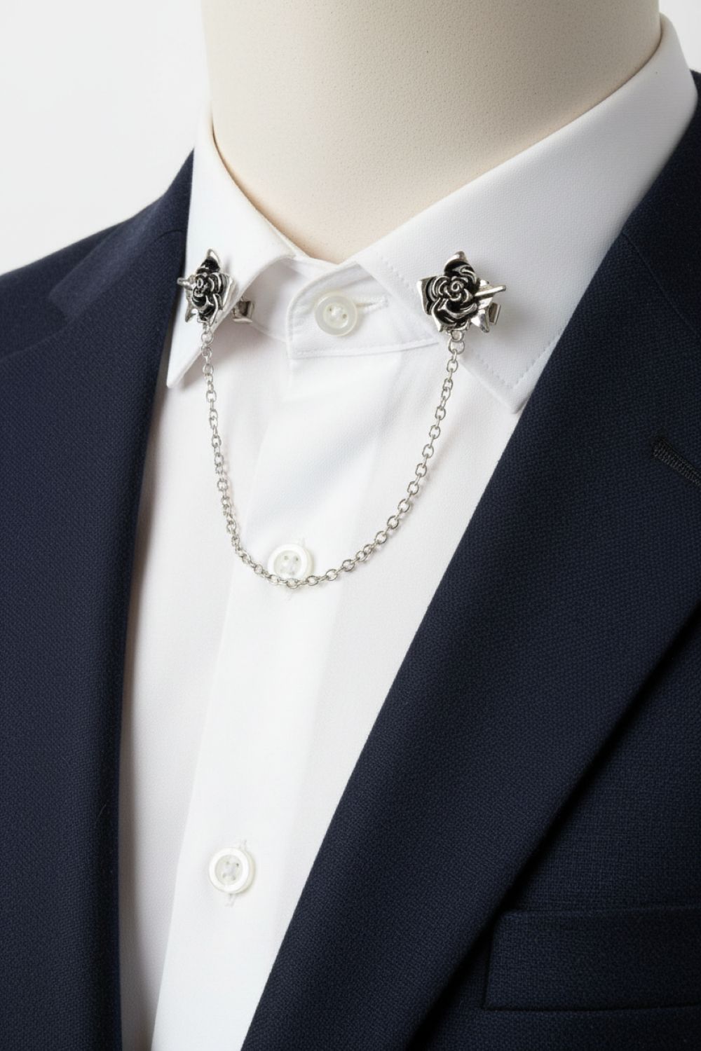 Mannequin wearing a navy blazer and white shirt with decorative rose lapel pins and a chain.