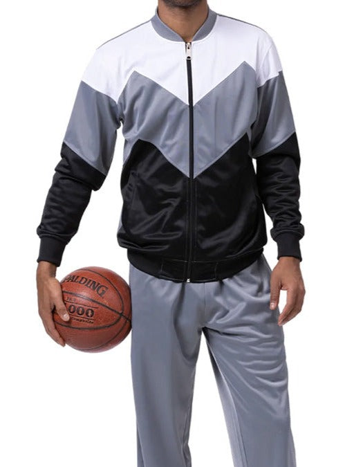 Person wearing a black, gray, and white tracksuit holding a basketball on a white background