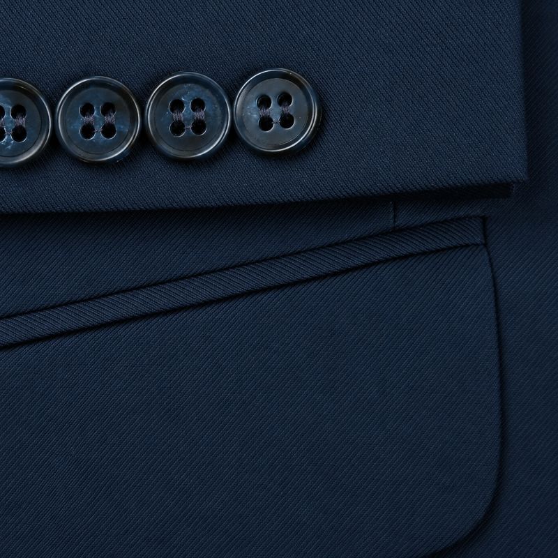 Close-up detail of a dark navy blazer fabric showing a pocket, a fold-over cuff, and four dark metallic buttons.