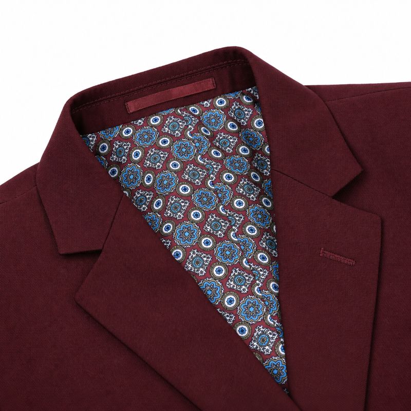 A close-up of a men's blazer in deep burgundy, showing the interior collar lined with a blue, white, and red paisley patterned fabric.