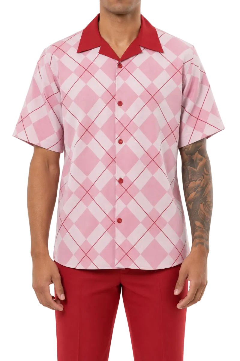 A man wearing a short-sleeve button-up shirt with a pink and white argyle pattern and a solid red collar, paired with red pants, against a plain white background.