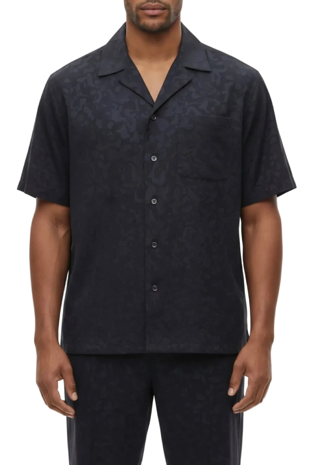 Man wearing a dark patterned short-sleeve shirt on a white background