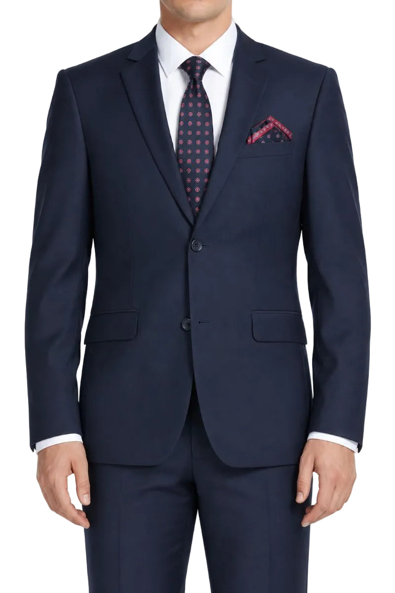 A man wearing a navy blue two-piece suit with a white dress shirt, a navy and red patterned tie, and a matching pocket square, shown against a plain white background.