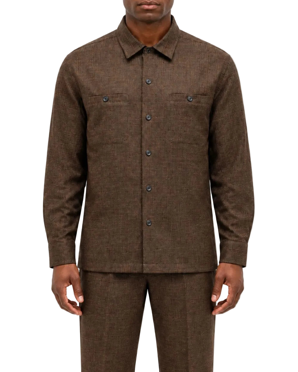 A man wearing a brown textured long-sleeve button-up shirt and matching brown trousers, shown from the chin down against a plain white background.