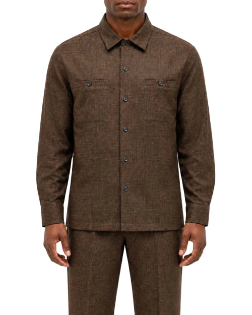 A man wearing a brown textured long-sleeve button-up shirt and matching brown trousers, shown from the chin down against a plain white background.