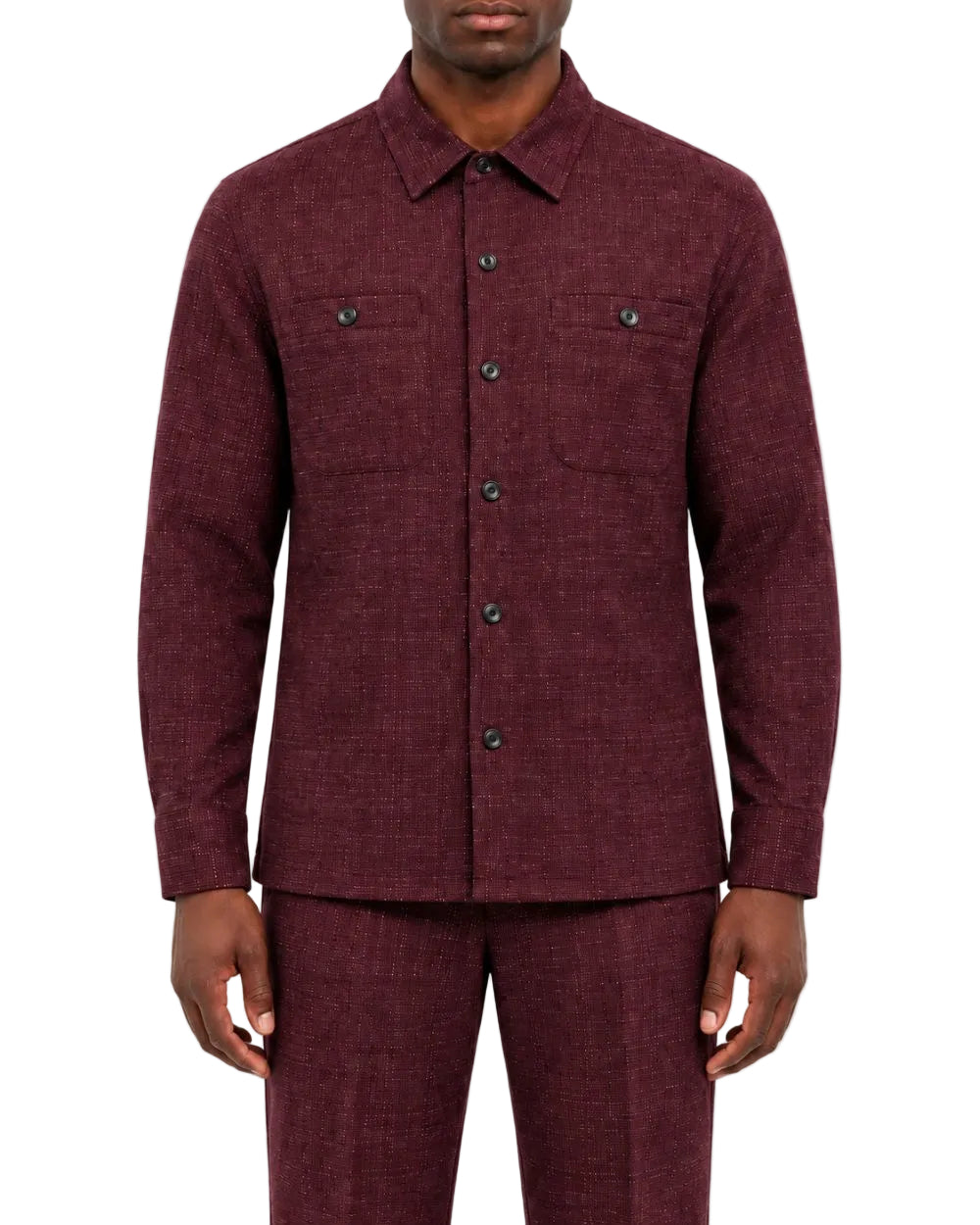 A man wearing a matching burgundy textured two-piece suit, featuring a long-sleeve button-up shirt jacket and coordinating trousers, shot against a plain white background.