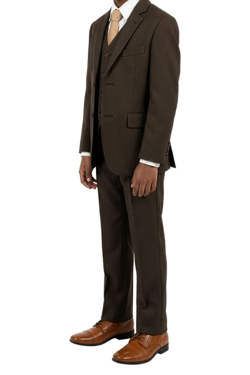 A boy wearing a five-piece brown-colored suit with a matching vest and trousers, a light dress shirt, a cream tie, and brown leather dress shoes, shown against a plain white background.