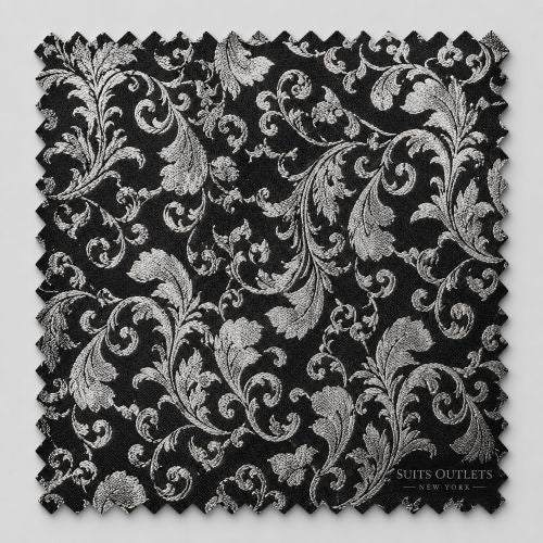 A square fabric swatch with a black background and an ornate silver damask pattern, featuring serrated edges and a 'Suits Outlets New York' logo in the bottom right corner.