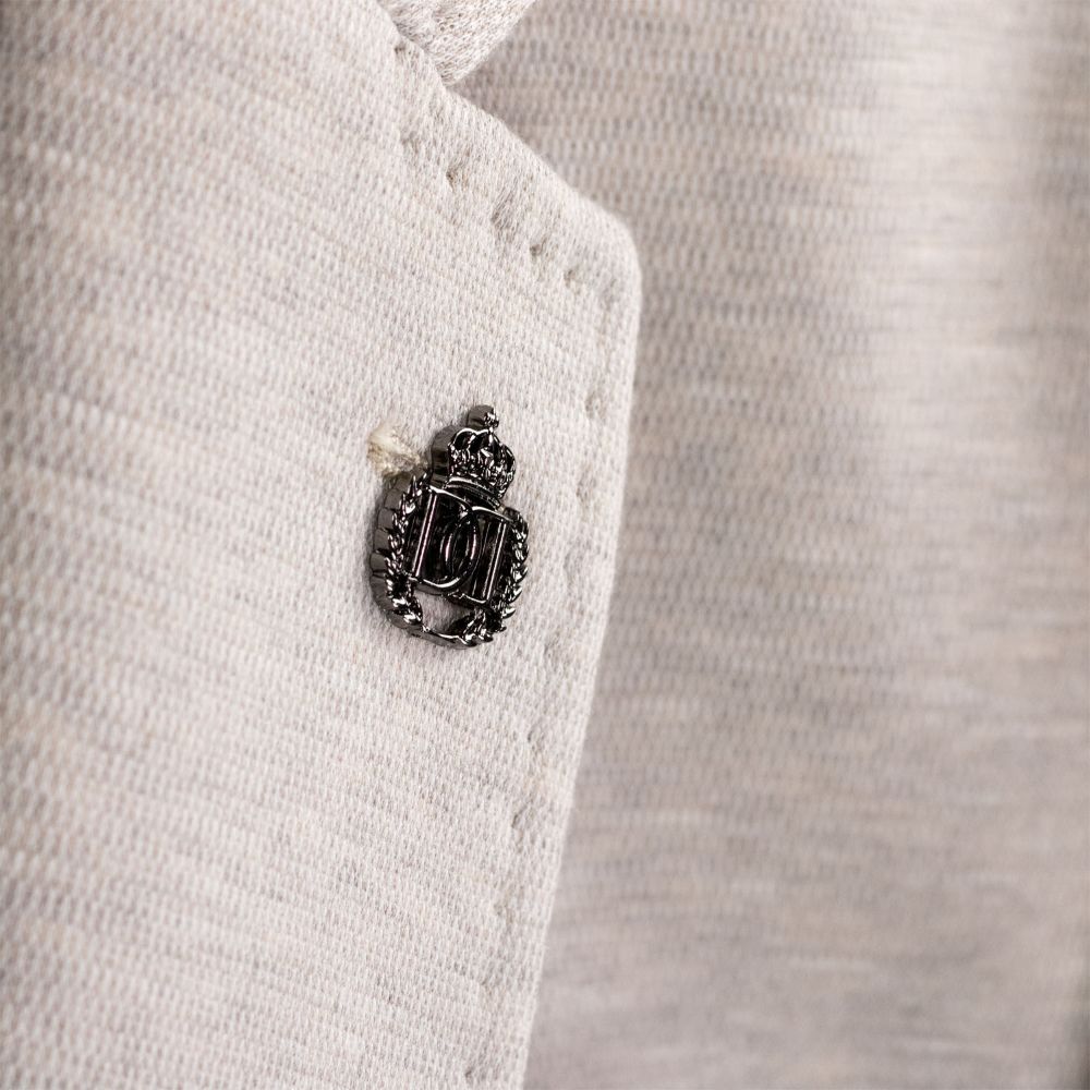 Silver beetle-shaped brooch on a textured beige fabric background