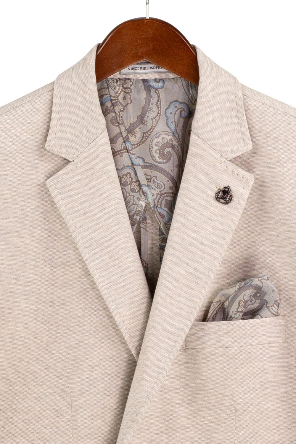 Beige blazer with paisley patterned lining and pocket square on a hanger.