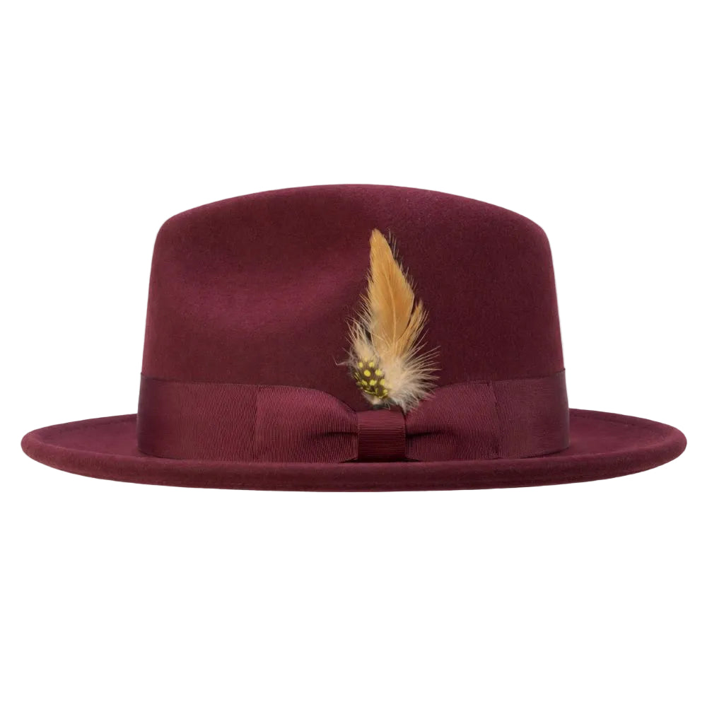 A burgundy felt fedora hat with a matching grosgrain ribbon band and bow, decorated with a tan feather and small gold bead accent, shown against a plain white background.