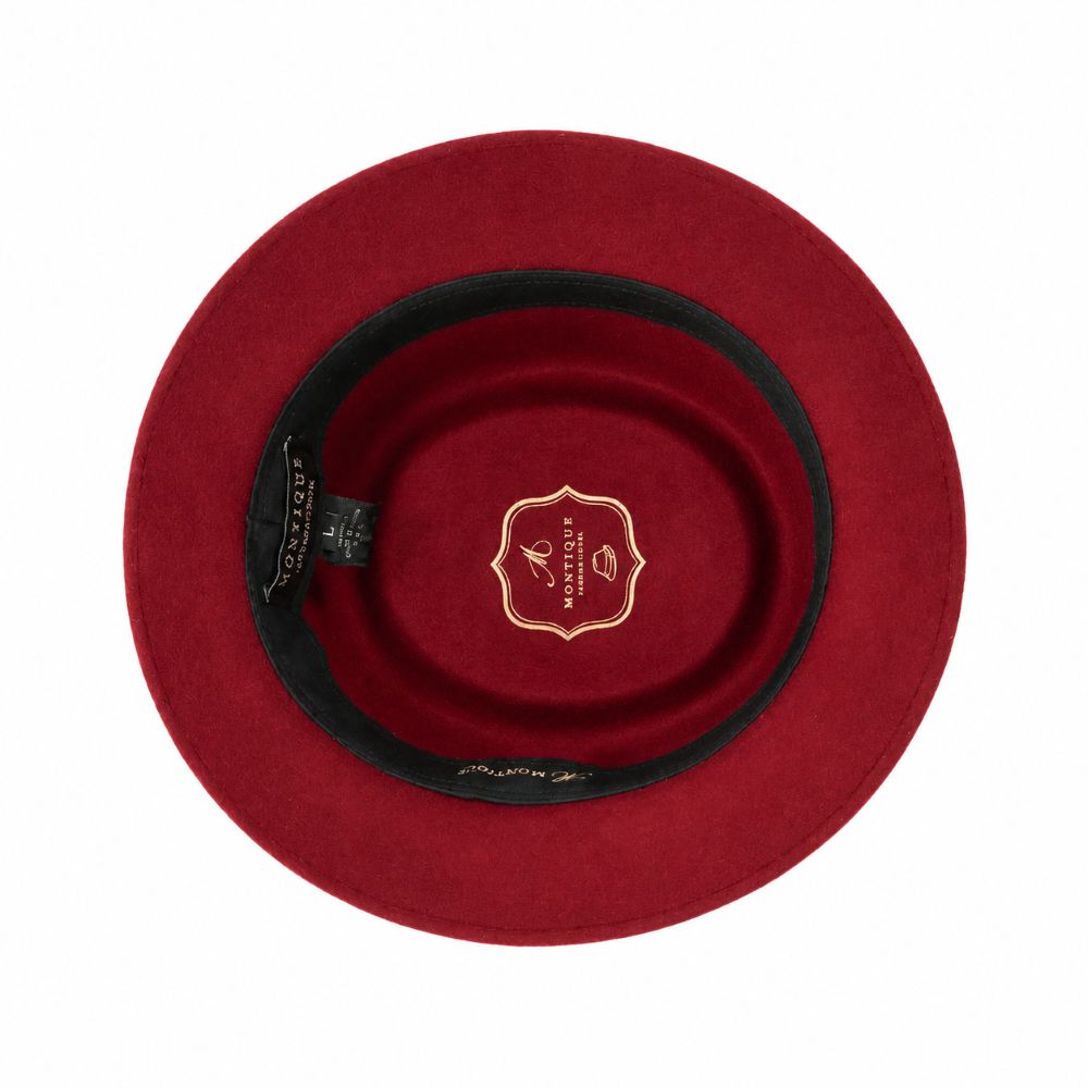 Top-down view of a red felt hat with a black band and a gold crest logo in the center, set against a plain white background.