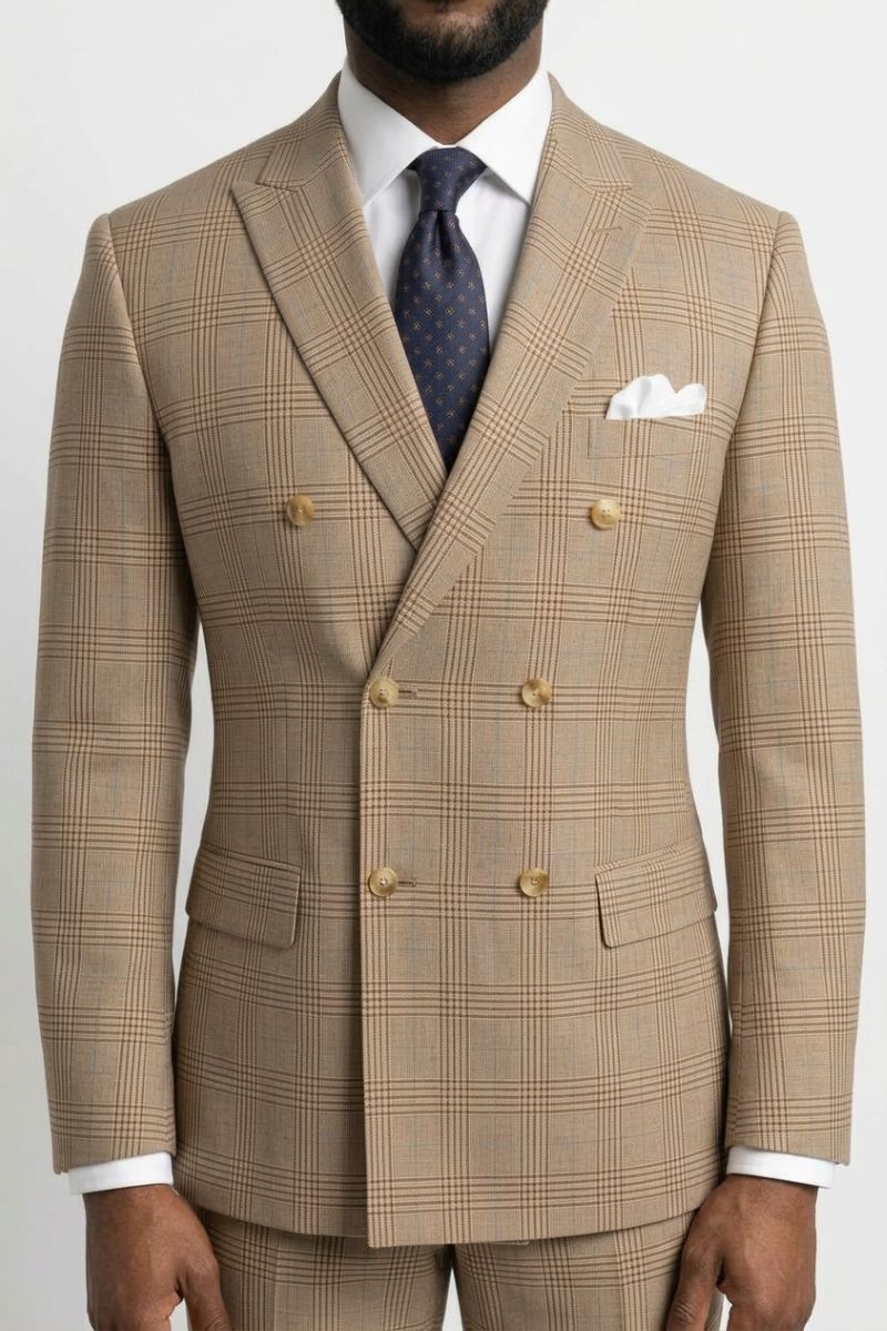 A man wearing a beige double-breasted suit with a subtle brown windowpane plaid pattern, styled with a white dress shirt, a navy patterned tie, and a white pocket square.
