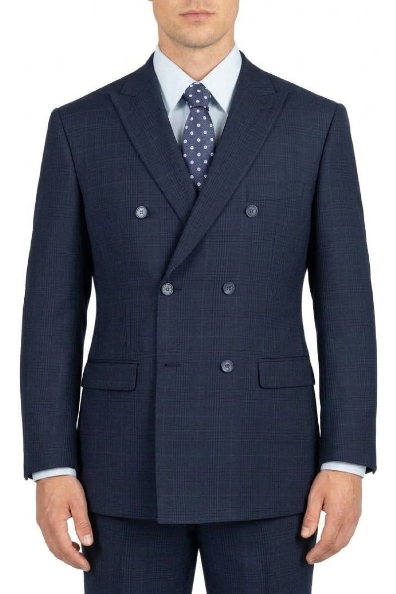 A man wearing a navy blue double-breasted suit jacket with a subtle windowpane check pattern, paired with a light blue dress shirt and a navy polka-dot tie, shown against a plain white background.