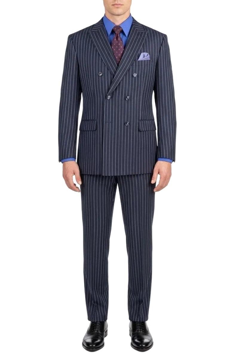 A man modeling a navy blue double-breasted suit with thin white pinstripes, paired with a blue shirt, a patterned purple tie, and a matching pocket square, set against a plain white background.