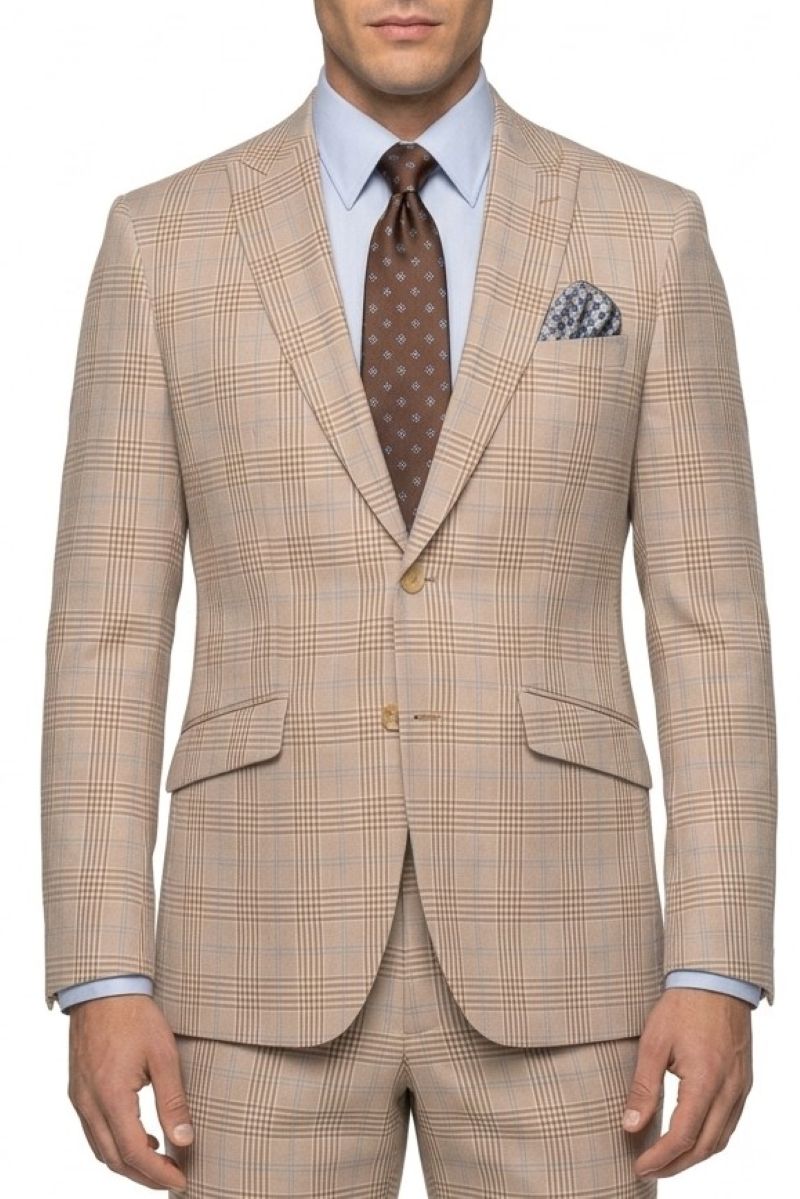 A man wearing a beige and brown plaid suit jacket with matching trousers, a light blue dress shirt, a brown patterned tie, and a matching pocket square, shown from the waist up against a white background.