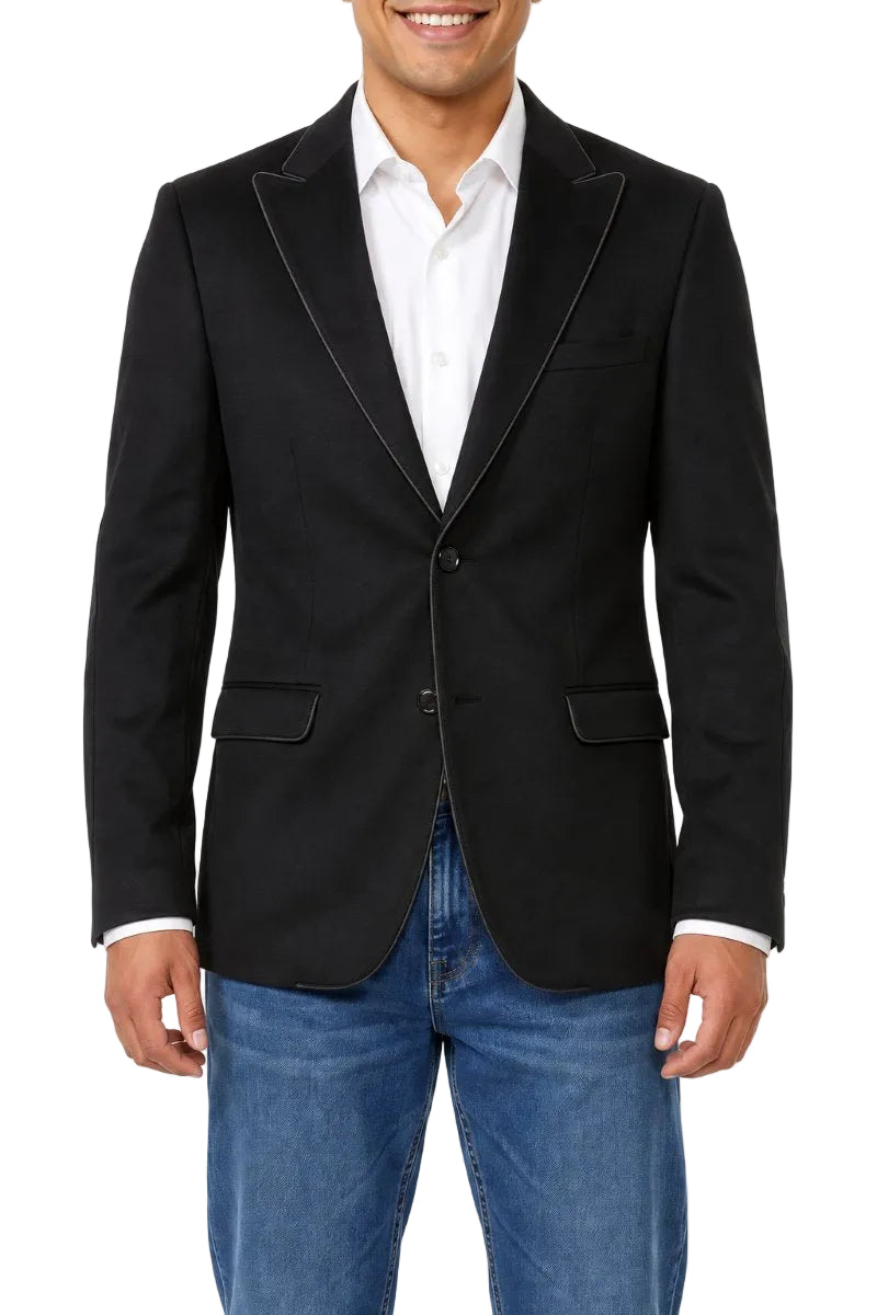A man wearing a black blazer with black satin lapels, a white dress shirt, and blue jeans, shown from the waist up against a plain white background.