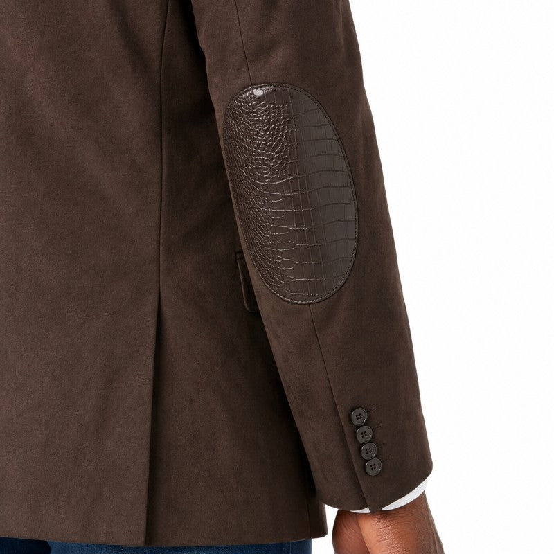Close-up of a brown blazer sleeve showing a crocodile-embossed elbow patch and three dark buttons on the cuff, with a white shirt edge visible at the wrist.