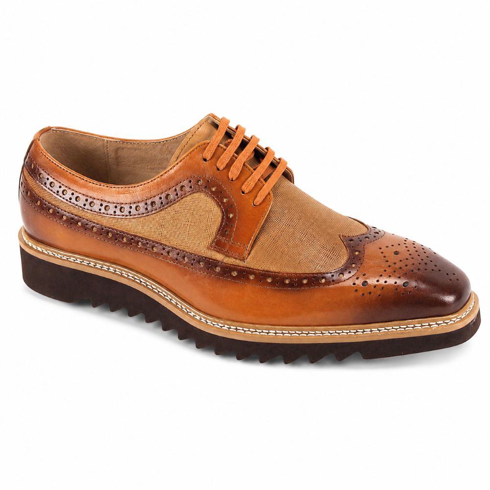 A men's wingtip oxford shoe featuring a mix of smooth tan leather, textured canvas-like fabric panels, and dark brown brogue detailing, with matching tan laces and a dark brown lug sole.