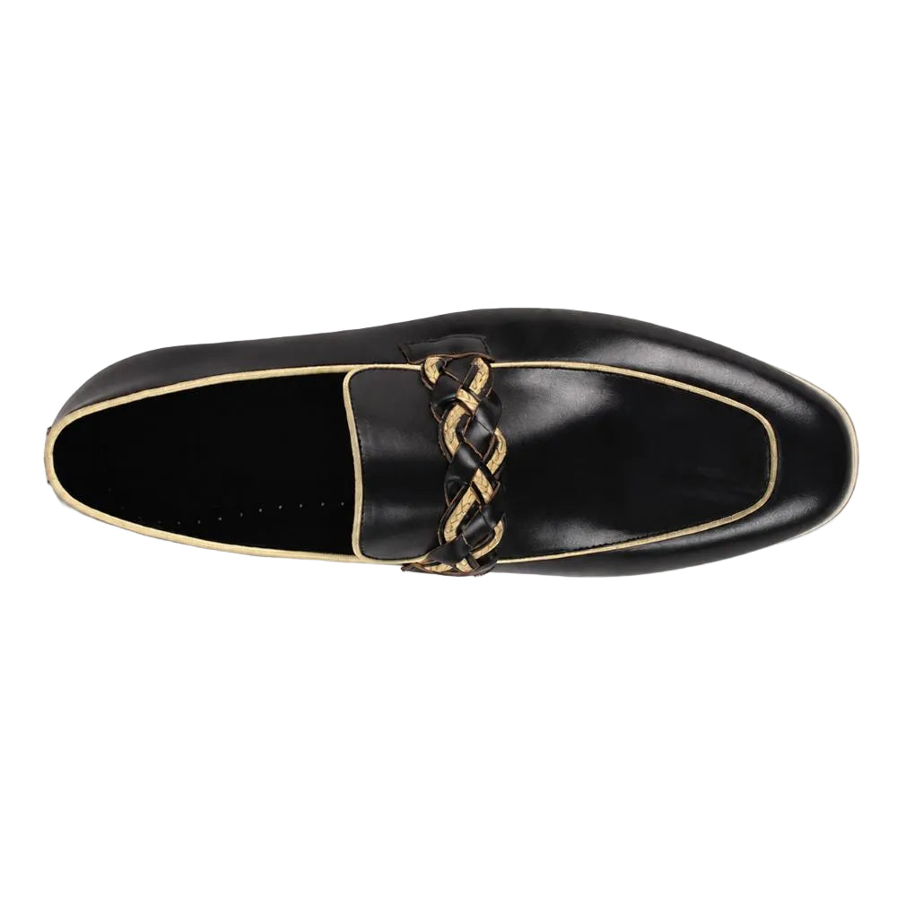A single black leather loafer shown from a top-down view, featuring a decorative braided tassel strap in black and gold over a gold piping outline, set against a plain white background.