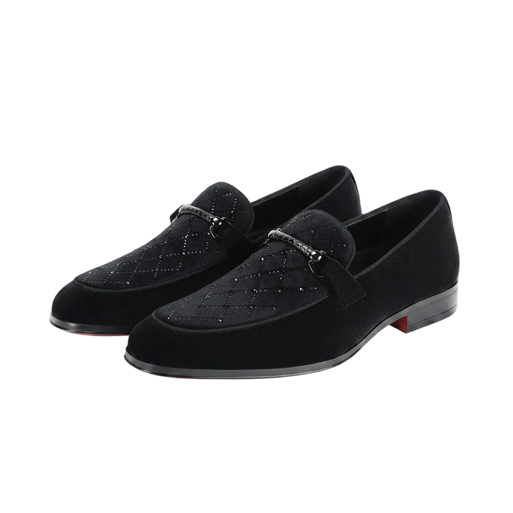 Pair of black velvet loafers with decorative elements on a white background