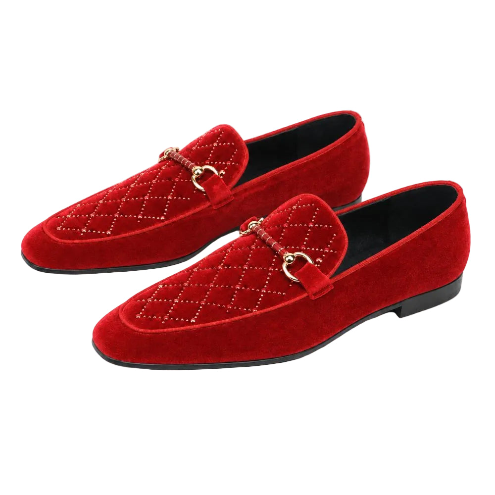 A pair of red suede loafers with a quilted diamond pattern, a small leather strap with a gold-tone horsebit detail, and black soles, shown on a plain white background.