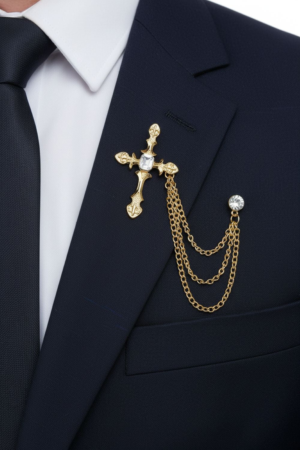 Gold cross brooch with chains on a black suit jacket