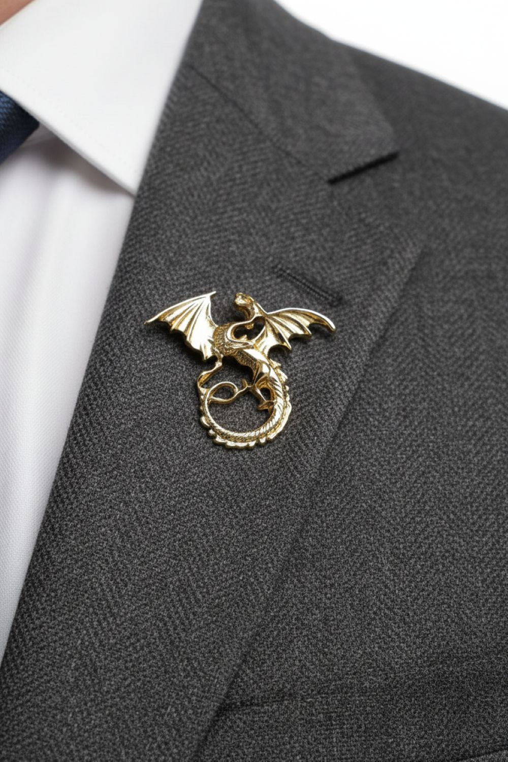 Gold dragon lapel pin on a gray suit jacket