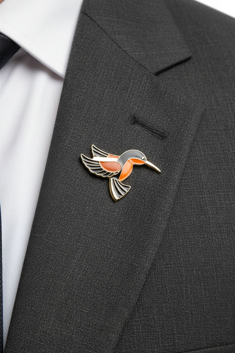 Bird-shaped lapel pin on a gray suit jacket