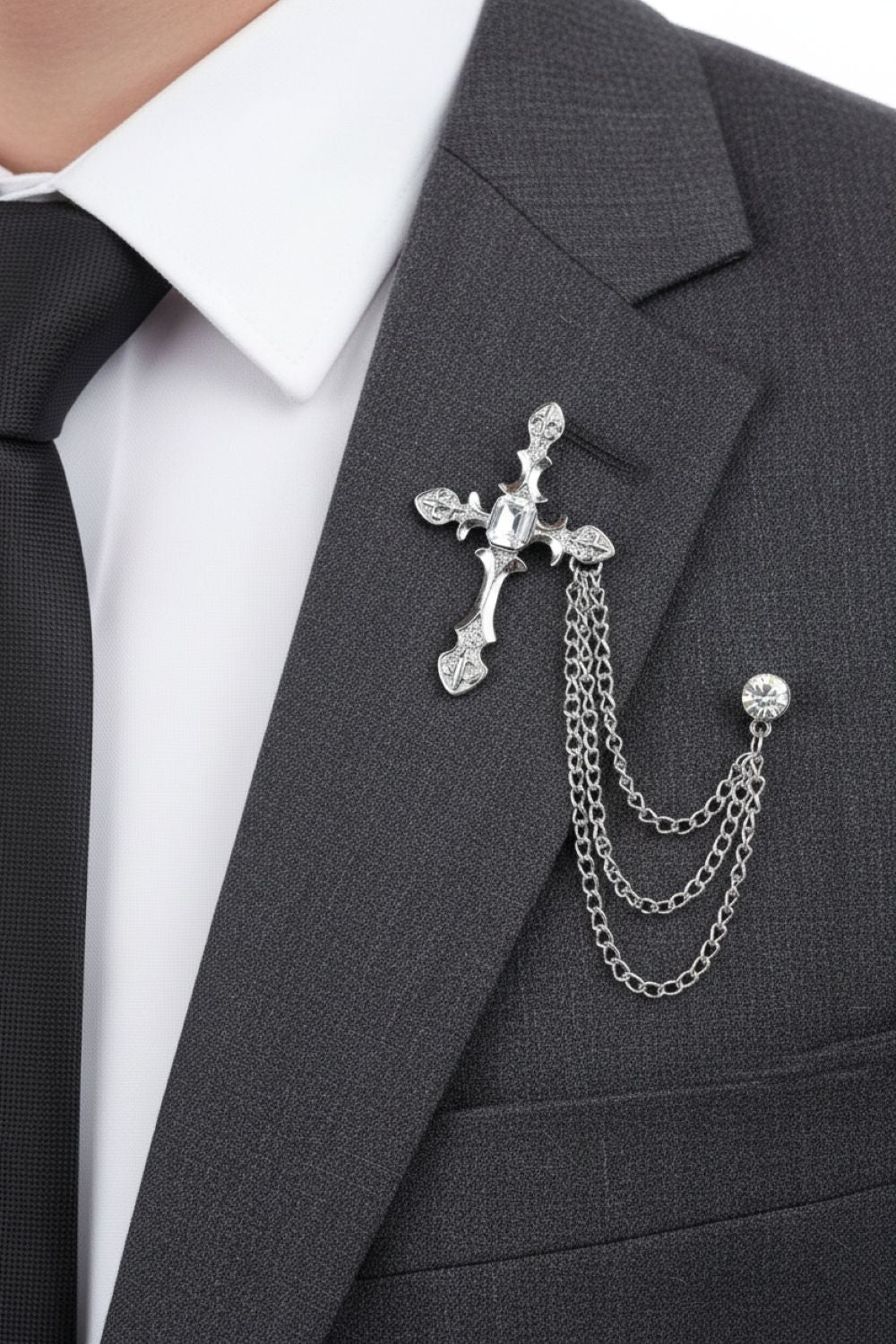 Silver cross brooch with chains on a gray suit jacket